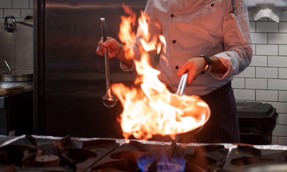 A man cooks cooking deep fryers in a kitchen fire. Process of food cooking in restaurant.